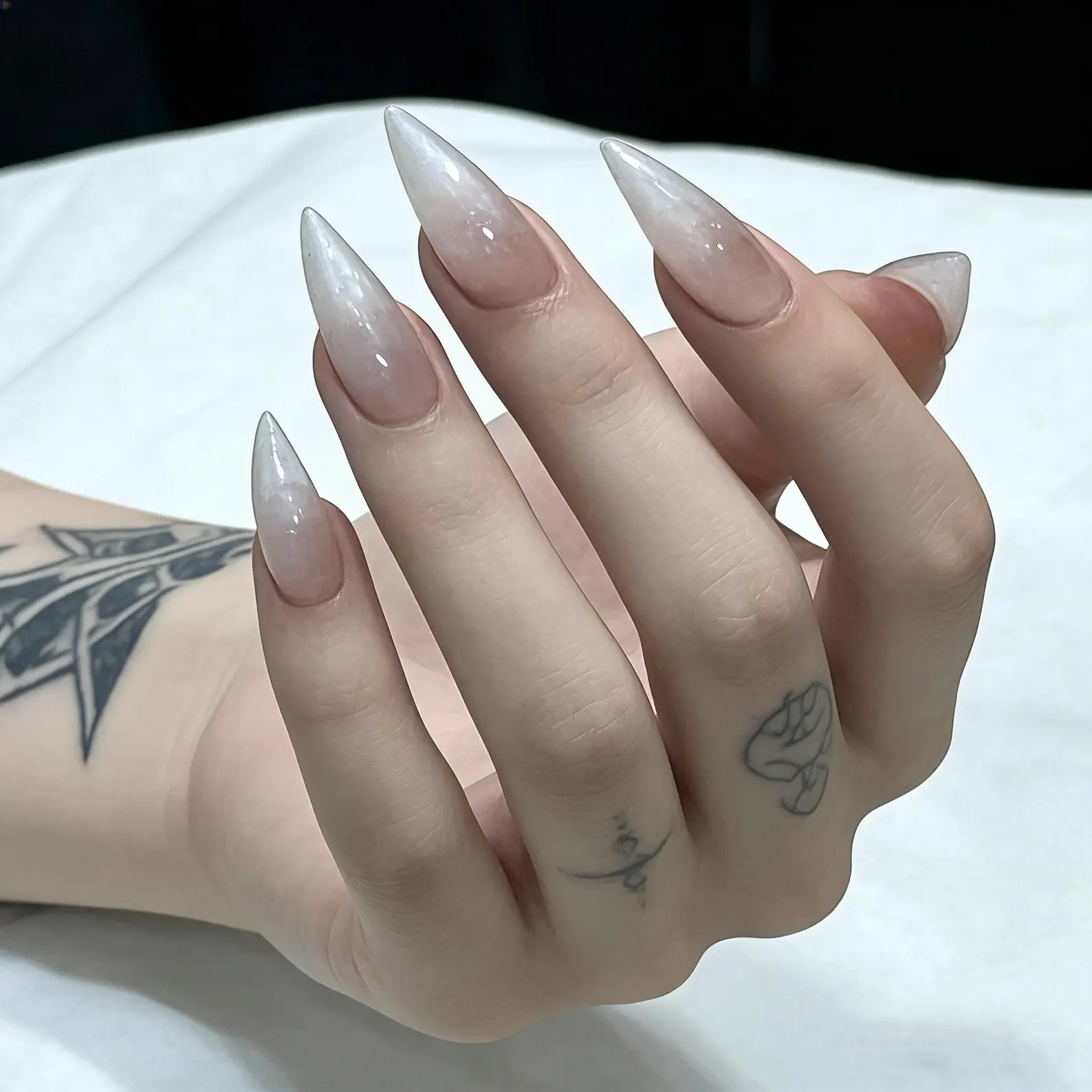 Close up glossy nude ombre stiletto press on nails, sheer transparent pointed tip false nail art detail shot