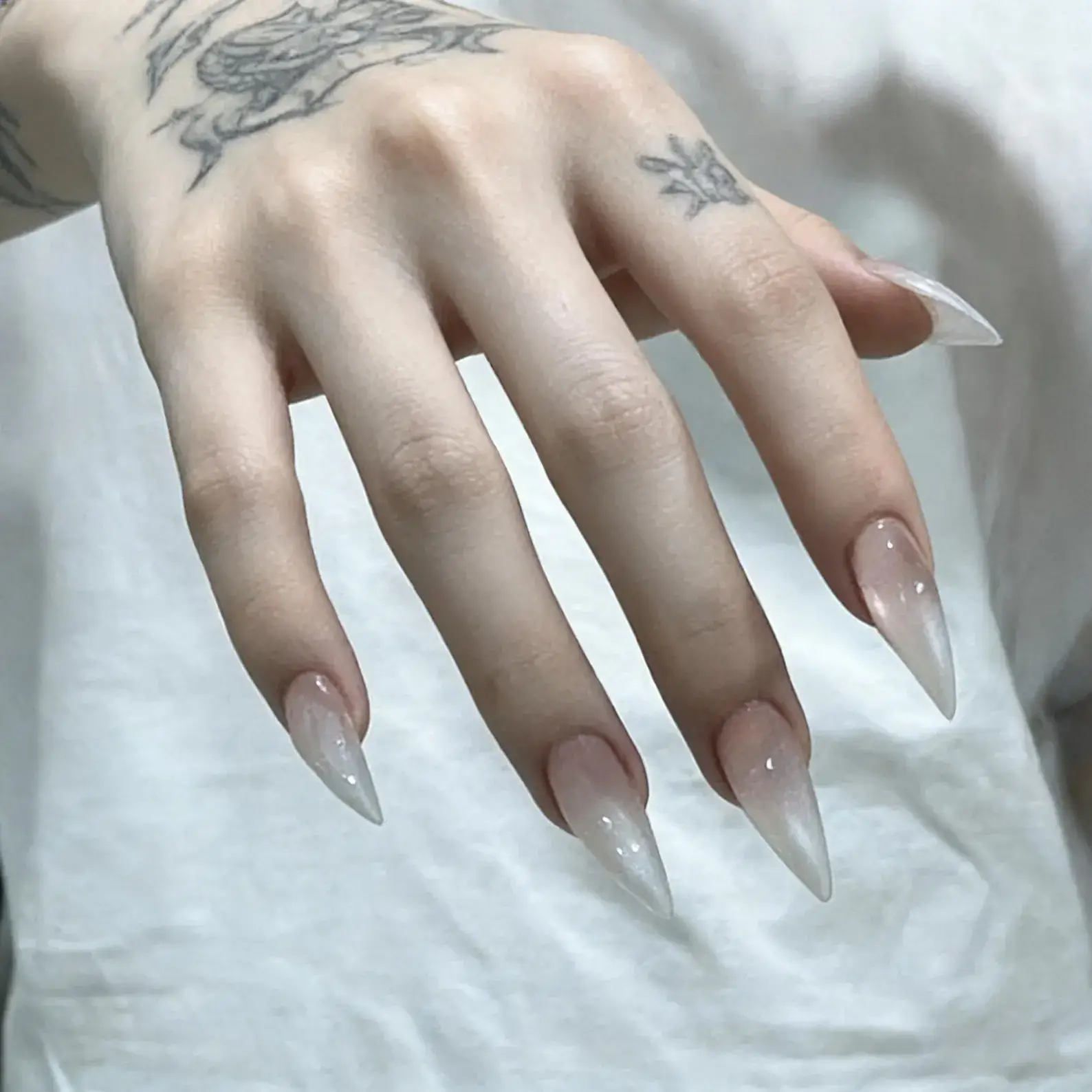 Crossed tattoo hands nude gradient stiletto press on nails, sheer clear long pointed fake nails neutral aesthetic