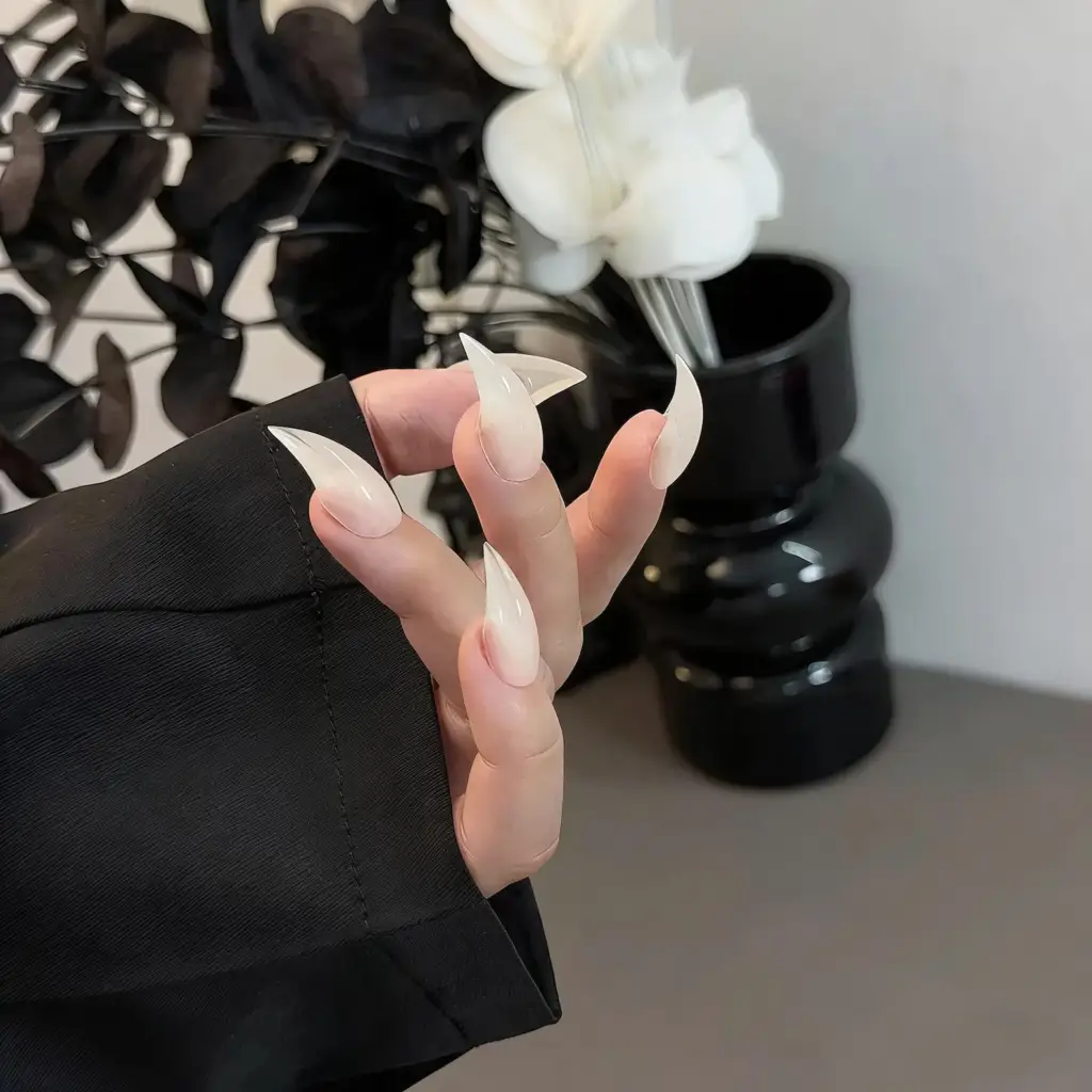 Aesthetic hand shot milky white sheer extra long stiletto press on nails, translucent sharp pointed fake nails dark floral decor background