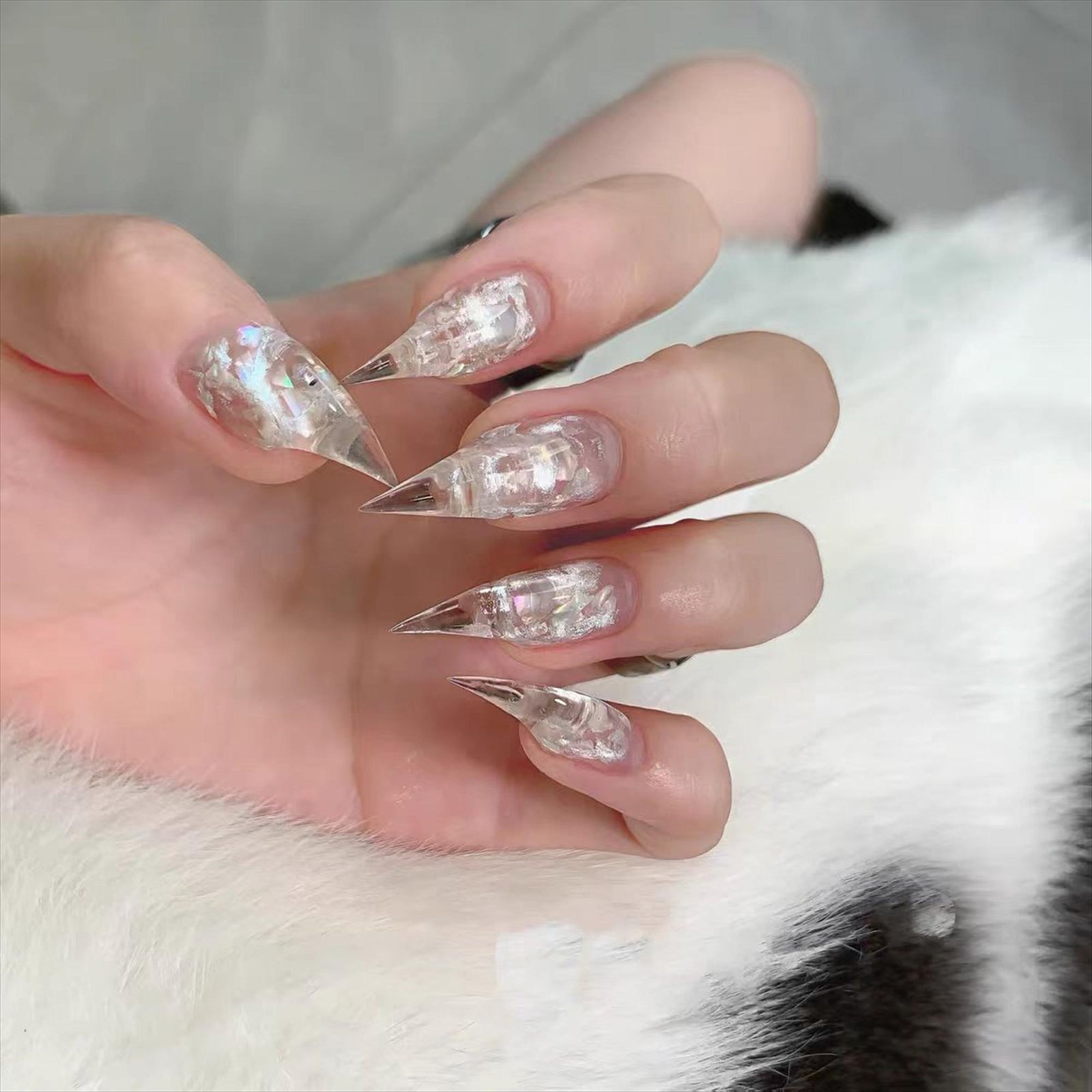 Clear nude press-on nails with silver glitter and crystal embellishments on hand