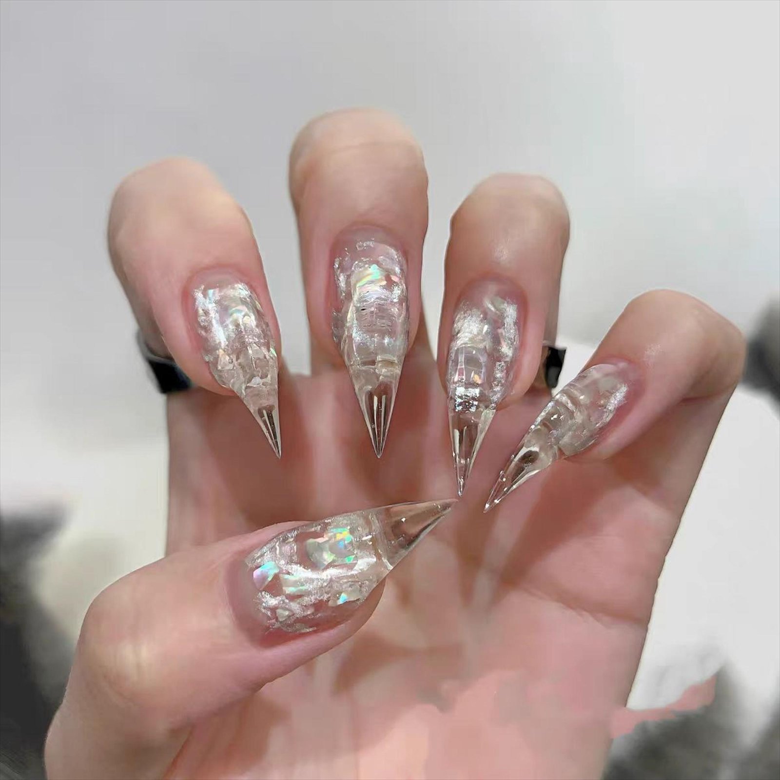Full hand wearing clear almond-shaped press-on nails with silver glitter nail art