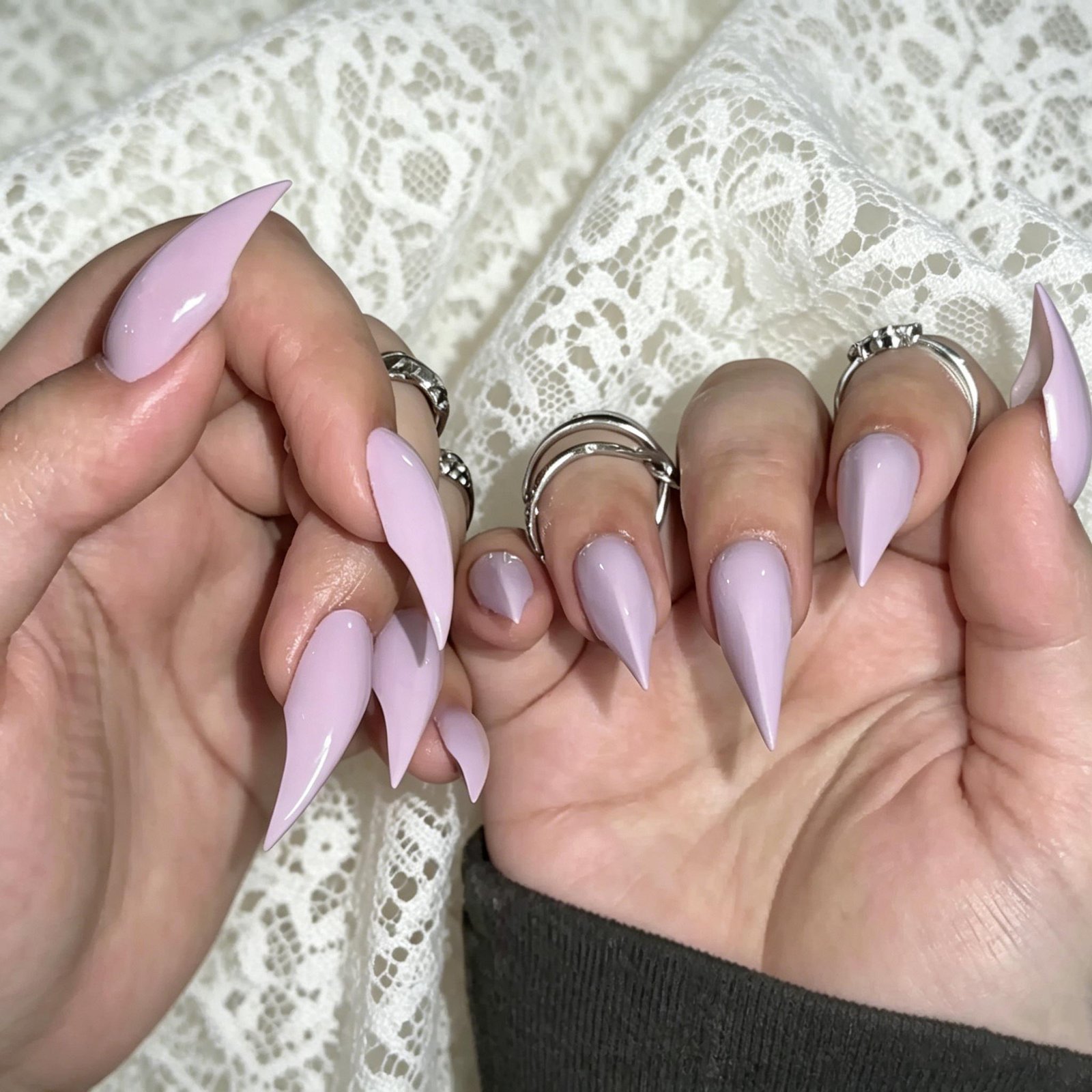 Long lavender stiletto press-on nails with minimalist glossy nail art on hands
