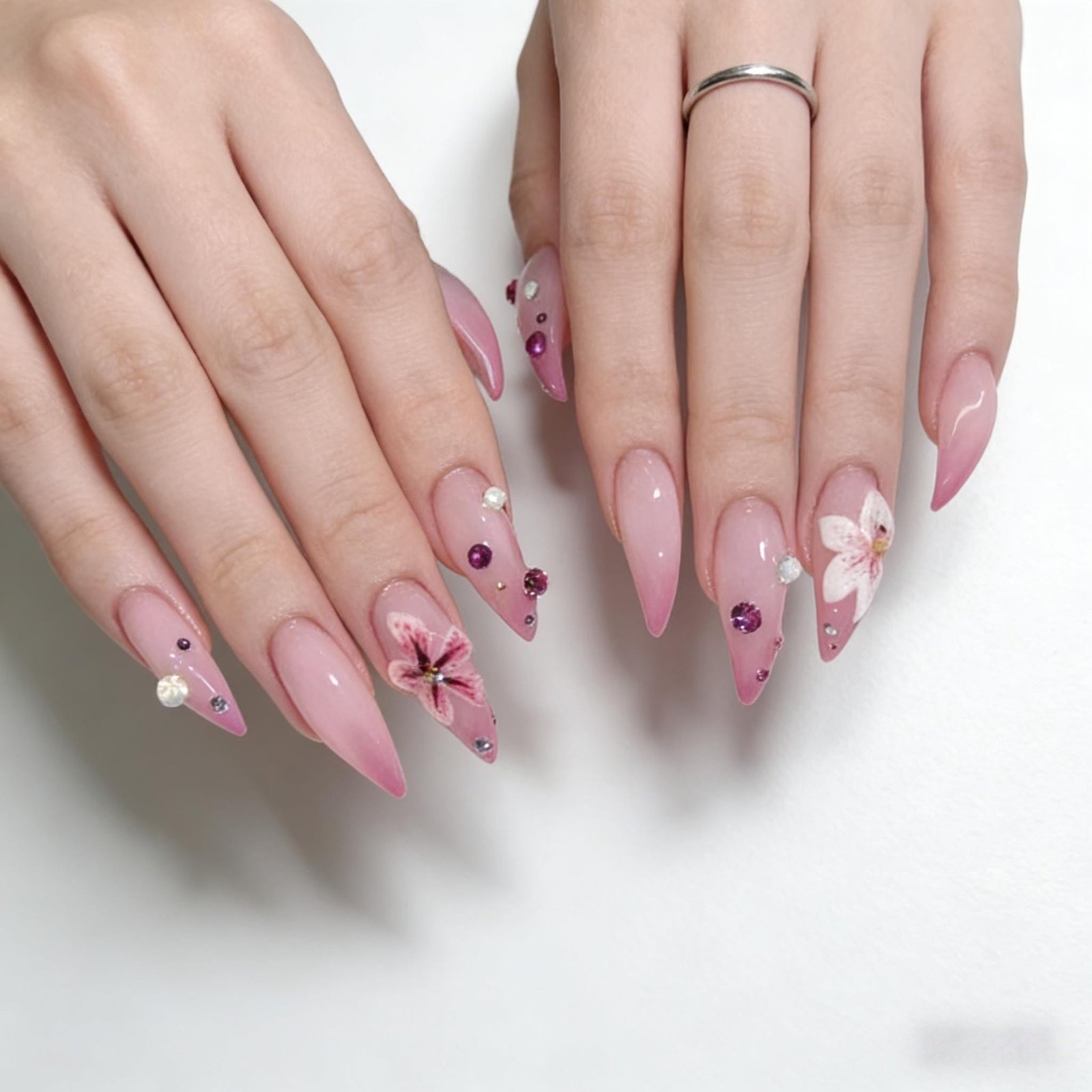 Straight-on shot of two hands fitted with matte pink floral art stiletto press on nails