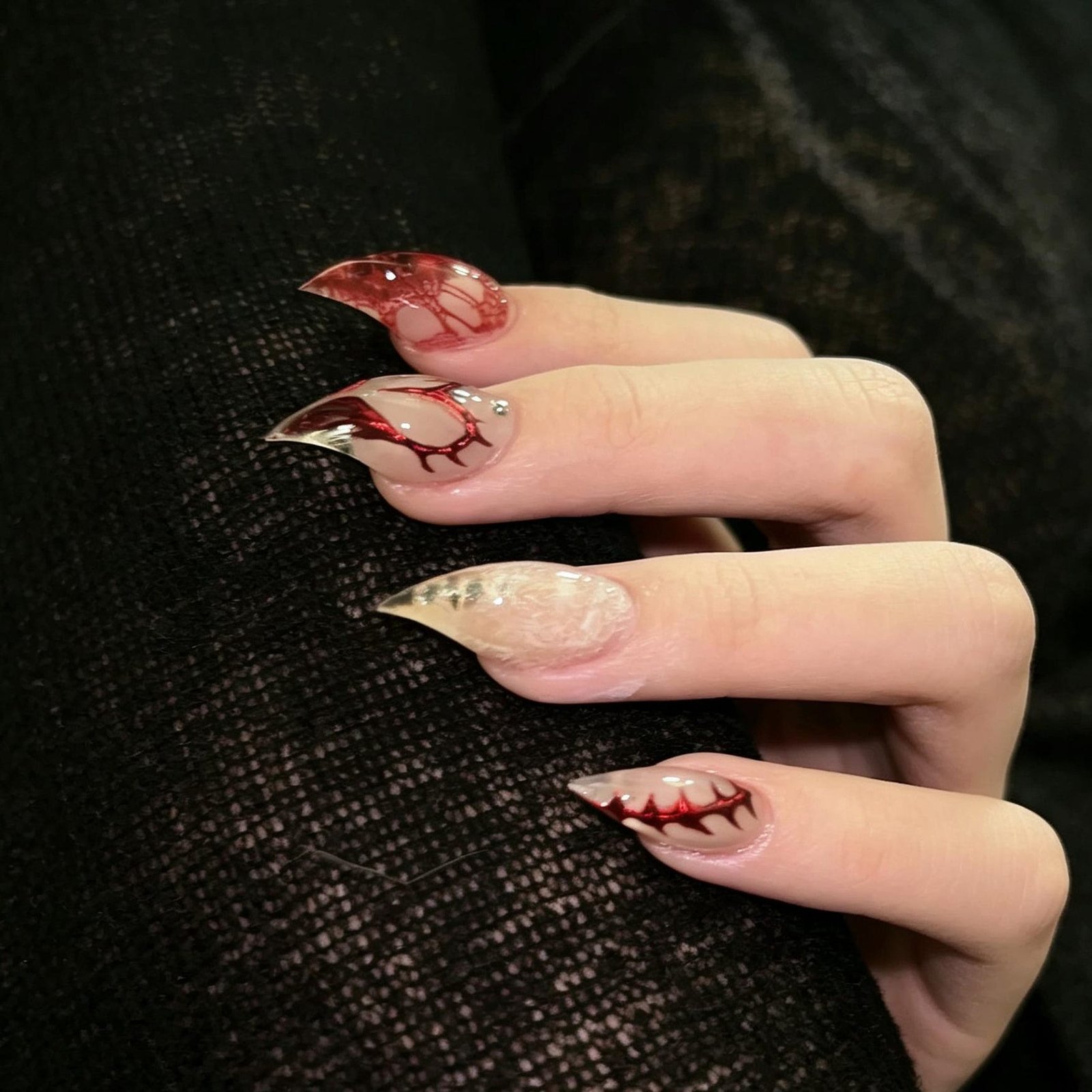 Hand wearing long red and black gothic press-on nails with floral 3D nail art