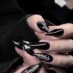 Close-up view of hands with black stiletto press on nails and silver graffiti detailing