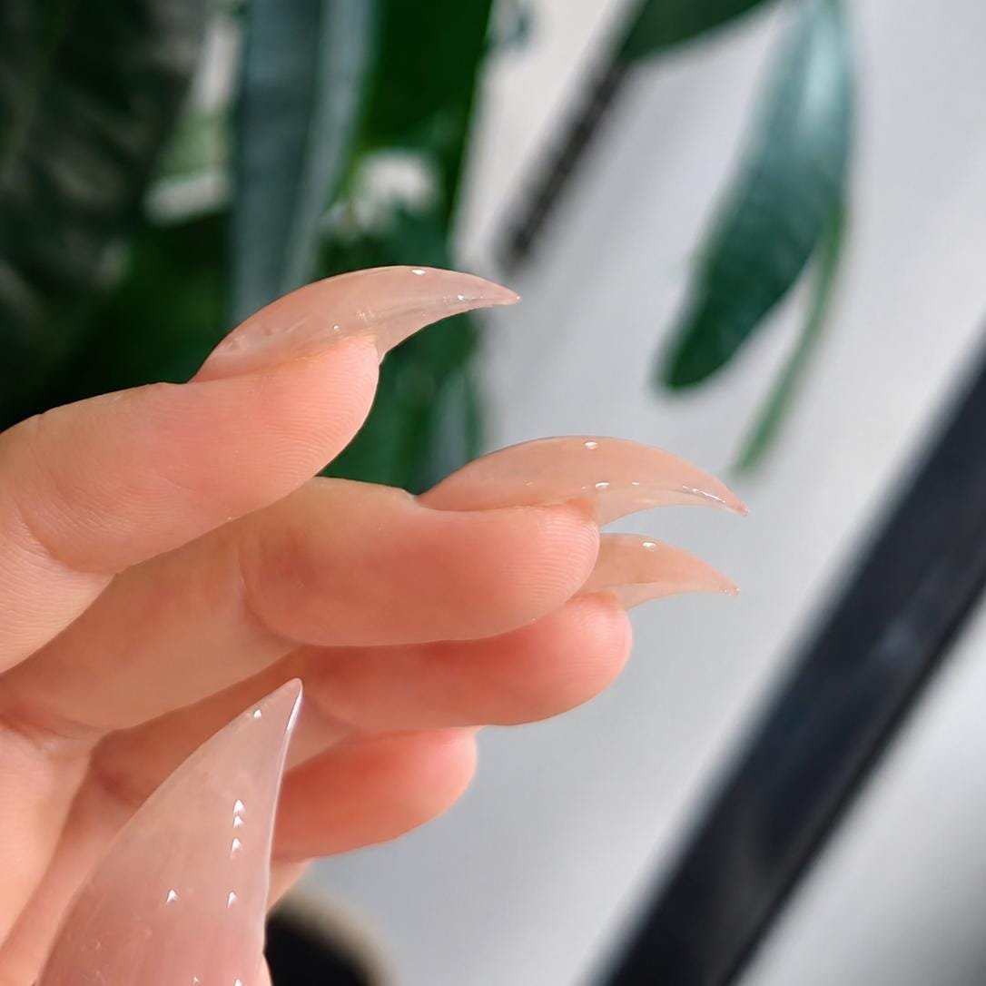 Close-up side view of fingers with nude pink french tip stiletto press on nails