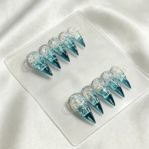 Handmade blue iridescent foil stiletto press on nails laid flat on white silk fabric