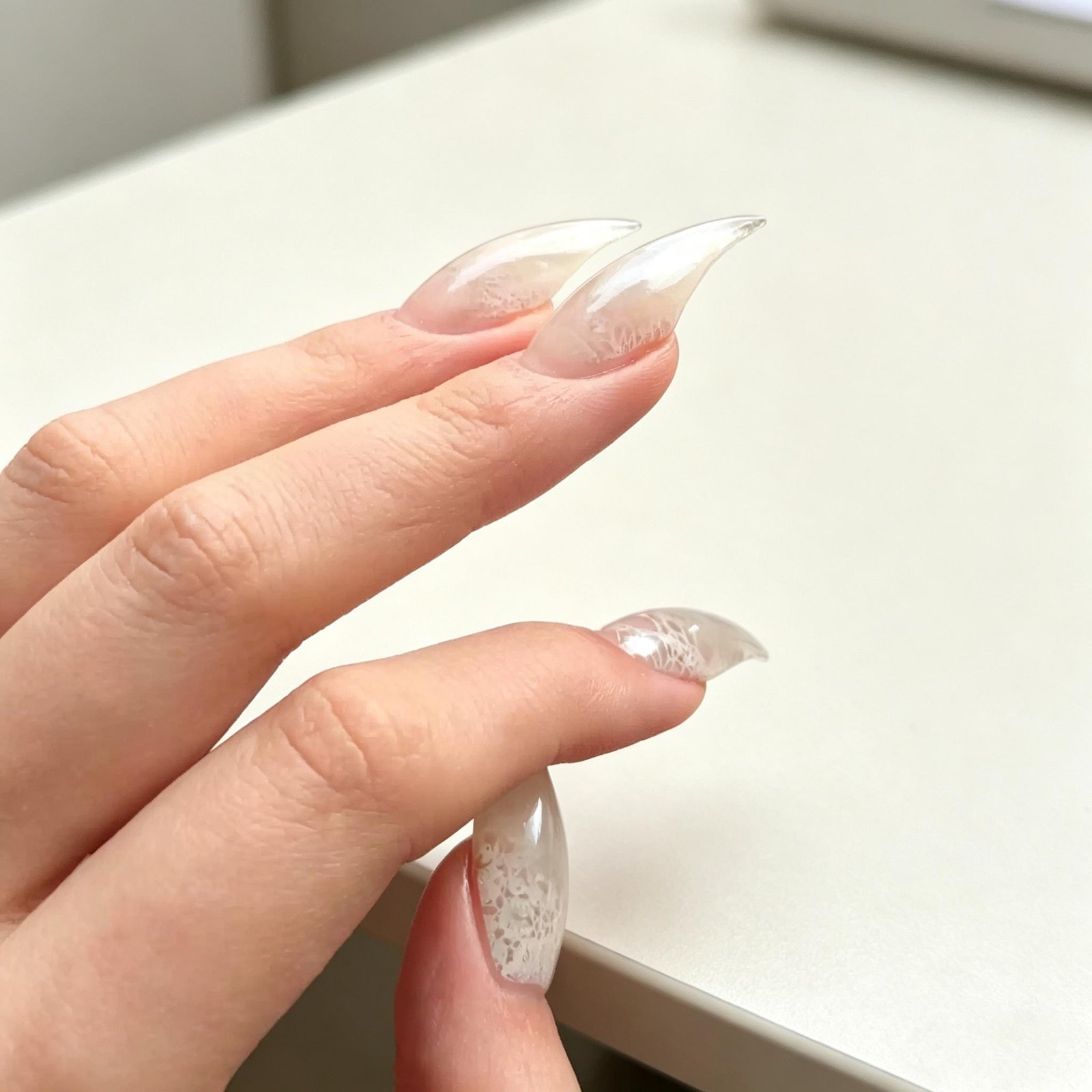 Close-up of white pearl chrome press-on nails with transparent glossy finish