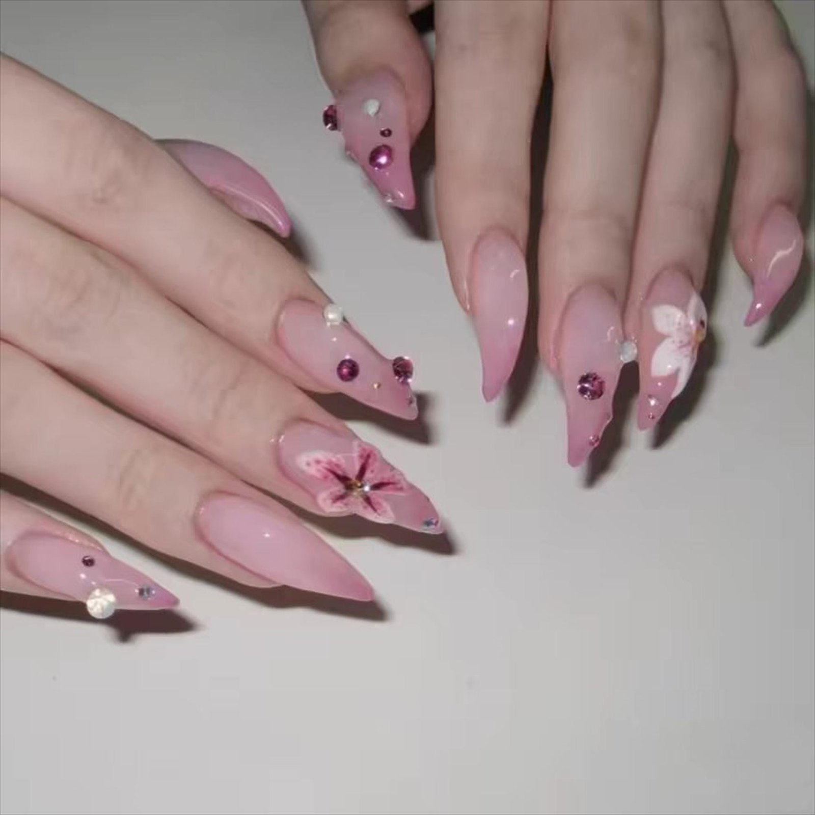 Flat lay closeup of pink floral stiletto press on nails worn on both hands