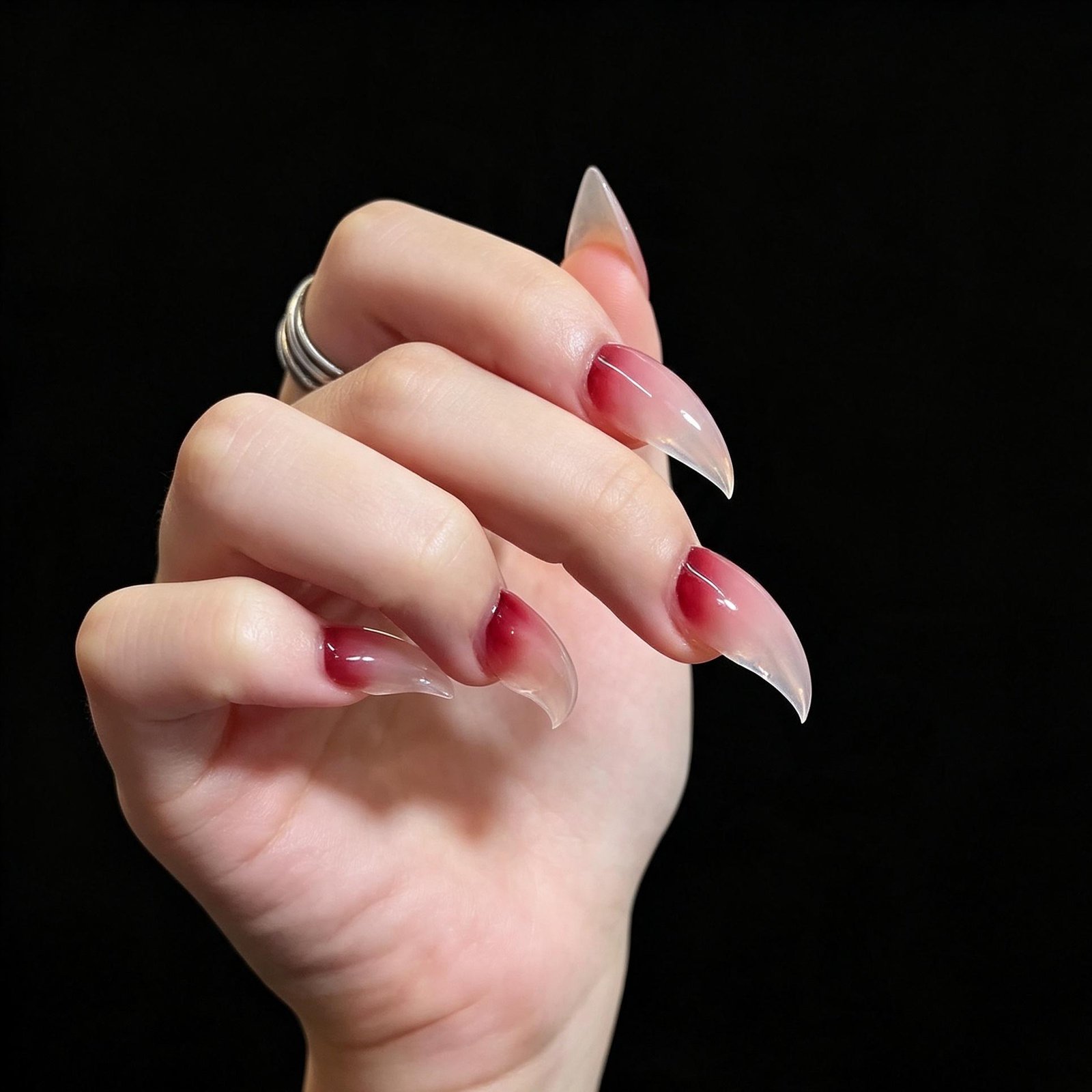 Clenched fist aesthetic shot pink blush gradient stiletto press on nails, sheer clear long pointed fake nails black background